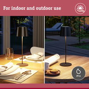 Black metal table lamp on wooden table set for dining, suitable for indoor and outdoor use with IP44 rating