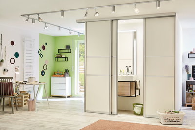 Modernes Wohnzimmer mit weißen Schiebetüren, grünem Wandakzent und Paulmann LED-Schienenbeleuchtung.