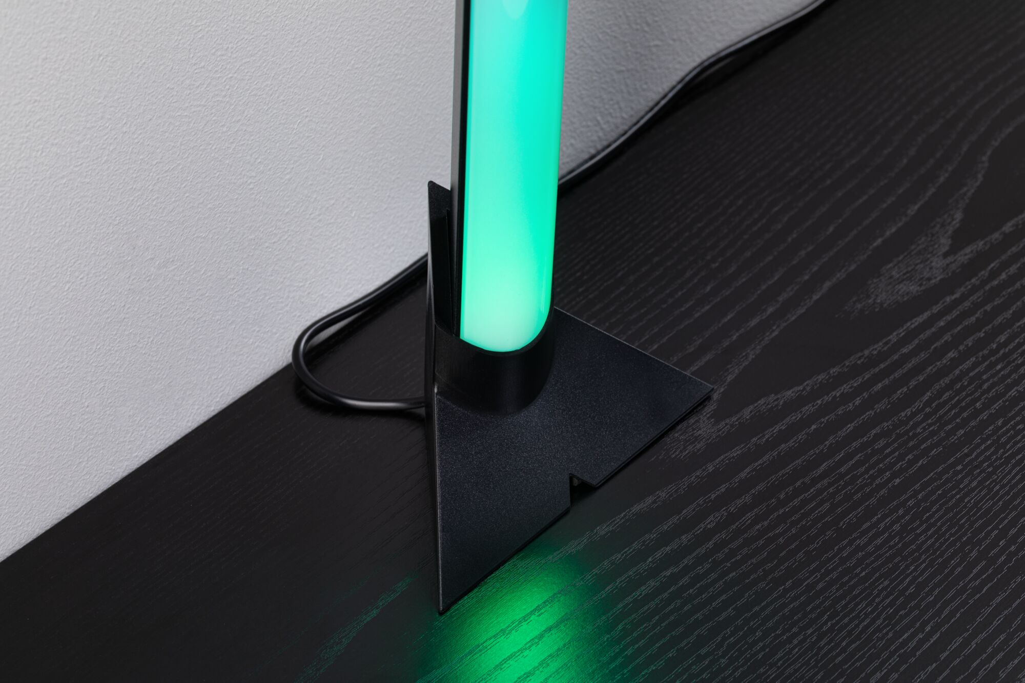 Lampadaire LED noir avec lumière verte sur table en bois foncé pour éclairage moderne