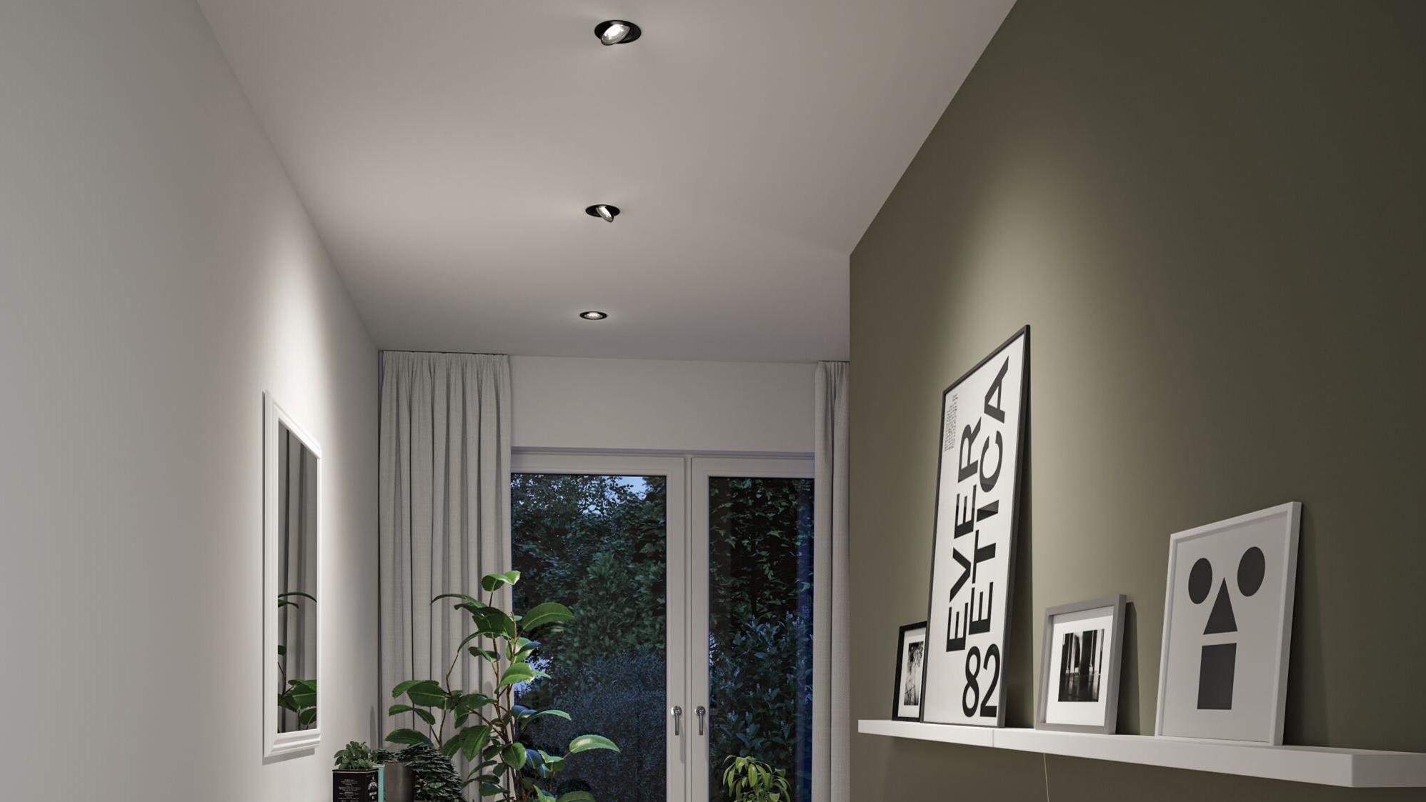 Drei schwarze Einbauleuchten in weißem Raum mit grüner Wand und moderner Wanddeko beleuchten Fensterbereich.