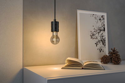 Suspension noire avec ampoule claire au-dessus d'une table blanche avec livre et déco dans le salon