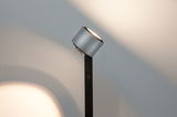 Modern floor lamp with silver aluminum head and black stand, emitting warm white LED light.