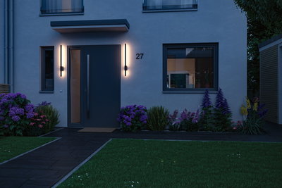 Modern house entrance with dark door and two slim wall lights emitting warm white LED light outside.