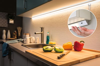 White LED under-cabinet light with warm white glow above kitchen sink and cutting board with peppers