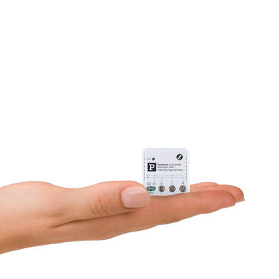 Small white electronic control device on open palm, compact lighting control module