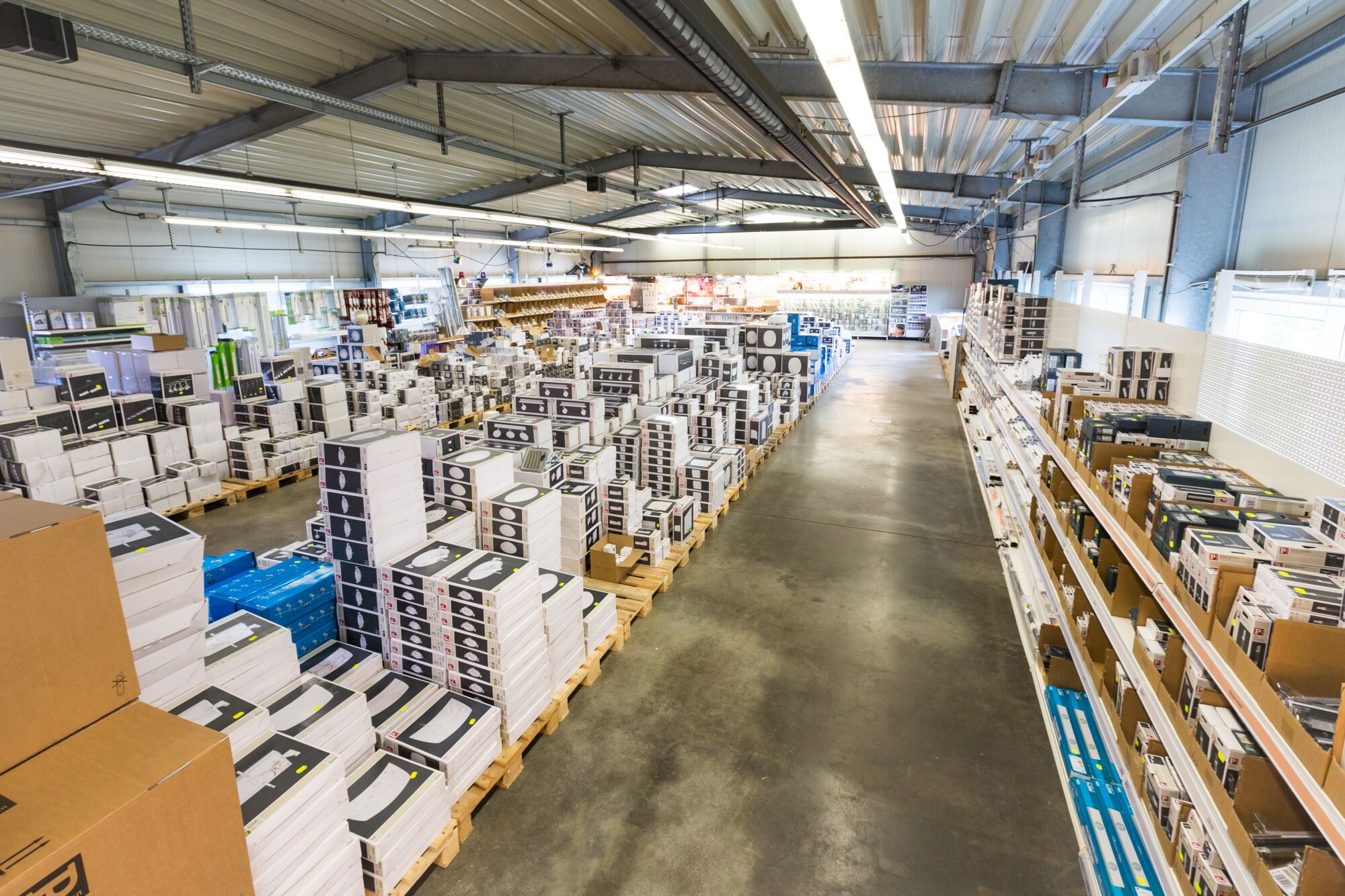 Grand entrepôt rempli de produits d'éclairage LED emballés empilés sur palettes et étagères