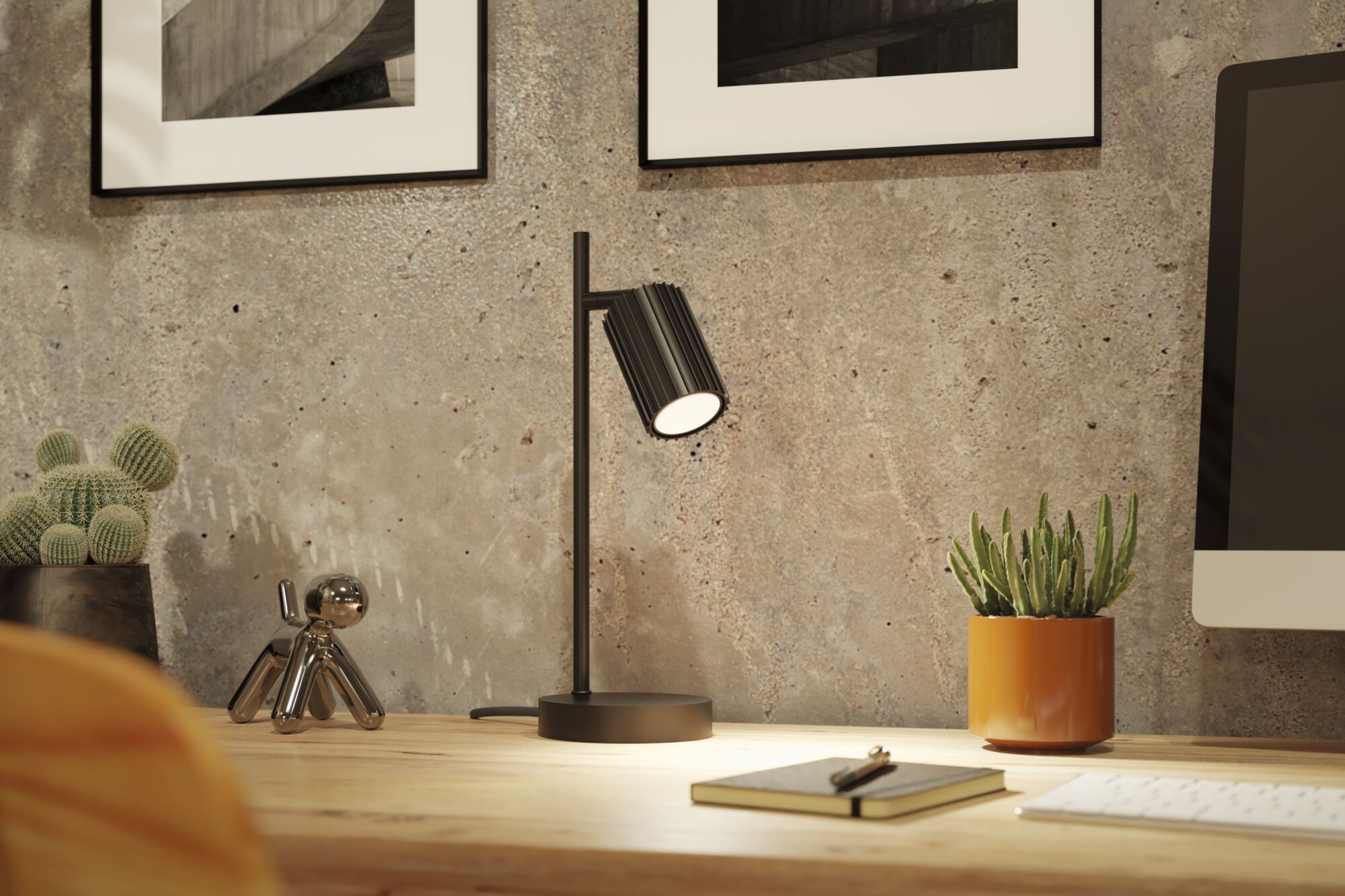 Schwarze Metall-Tischlampe mit geriffeltem Lampenschirm auf Holzschreibtisch mit Dekoration und Monitor