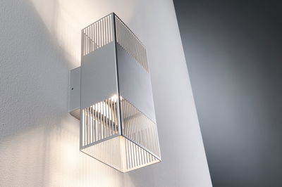 Modern silver metal wall light with vertical slats and warm white light for indoor lighting