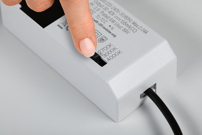 Doigt réglant l'interrupteur de température de couleur sur un pilote LED blanc avec 2700K, 3000K, 4000K