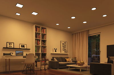 Salon moderne avec éclairage LED blanc chaud au plafond et mobilier confortable en tons bruns et beiges