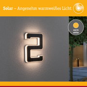 Solarbetriebene Hausnummer mit warmweißem Licht an grauer Wand für Außenbeleuchtung