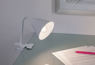 Witte metalen klemlamp met flexibele hals op glazen oppervlak, geschikt voor bureauverlichting.