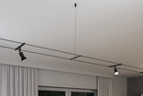 Sort minimalistisk kabelbelysningssystem med to justerbare spots på hvidt loft til moderne rumlys