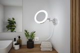 Ronde LED-wandspiegel met chromen metalen arm en warm wit licht in een moderne badkamer.