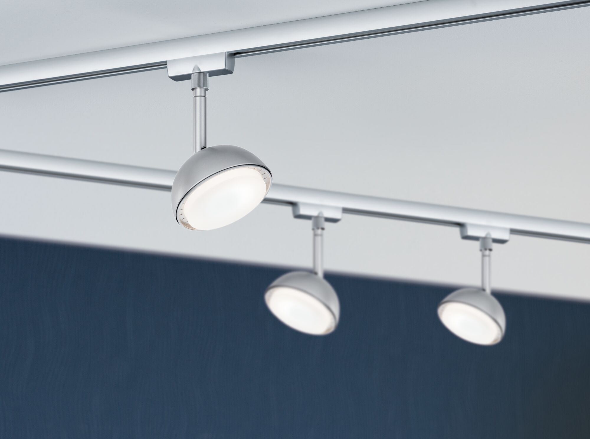 Tre sølvfarvede LED-spotlights på skinnesystem med hvidt lys til moderne rumbelysning.