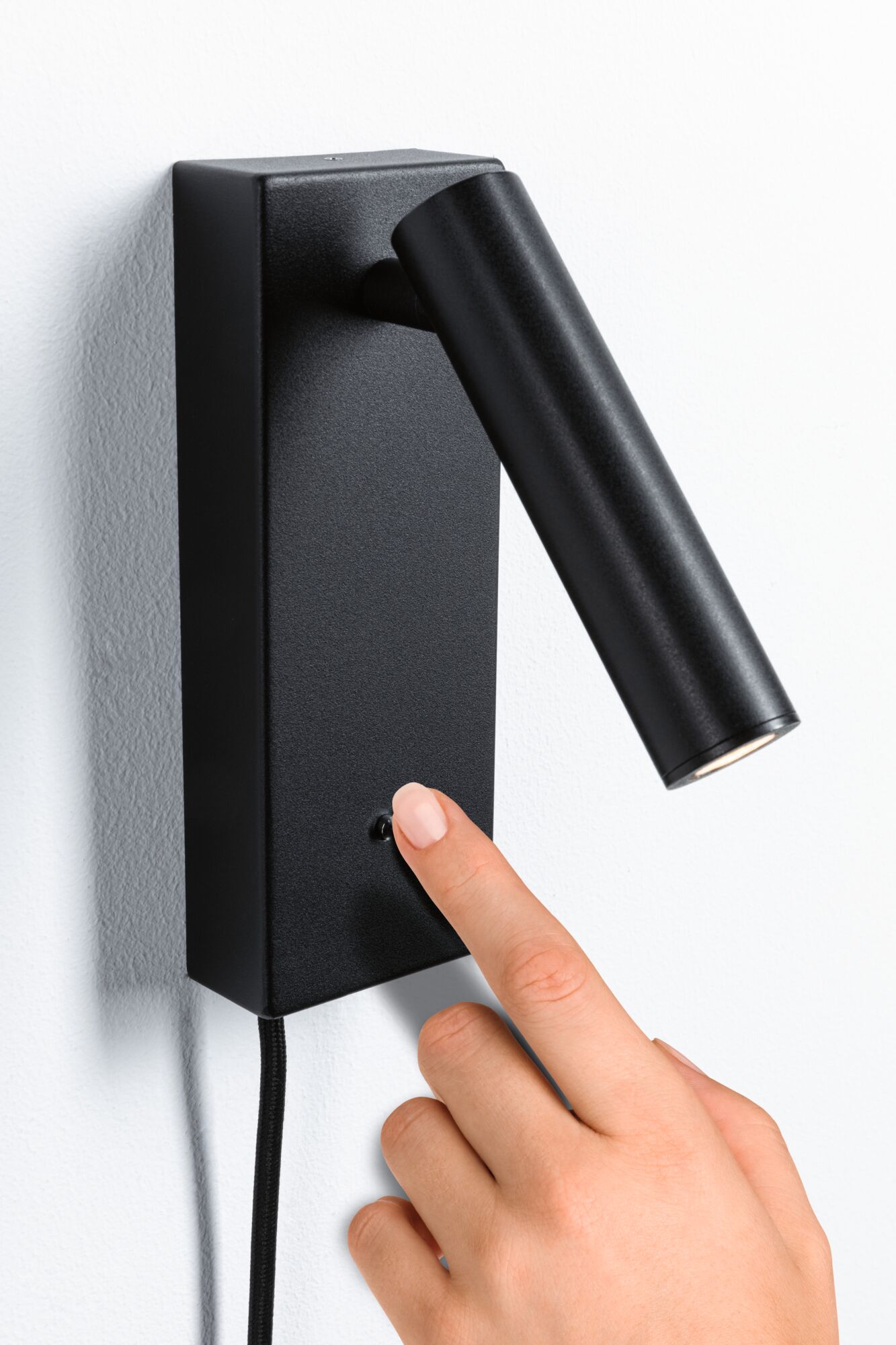 Zwarte metalen LED-wandlamp met verstelbare cilindervormige kop en kleine schakelaar aan de muur.