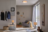 Modern living room with grey armchair, wooden ceiling light and warm lighting for cozy ambiance