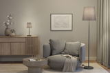 Cozy grey armchair with cushions and throw beside grey floor and table lamps in modern living room