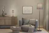 Gemütlicher grauer Sessel mit Kissen und Decke neben grauer Steh- und Tischlampe in modernem Wohnzimmer