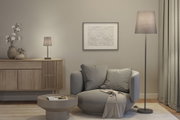Cozy grey armchair with cushions and throw beside grey floor and table lamps in modern living room