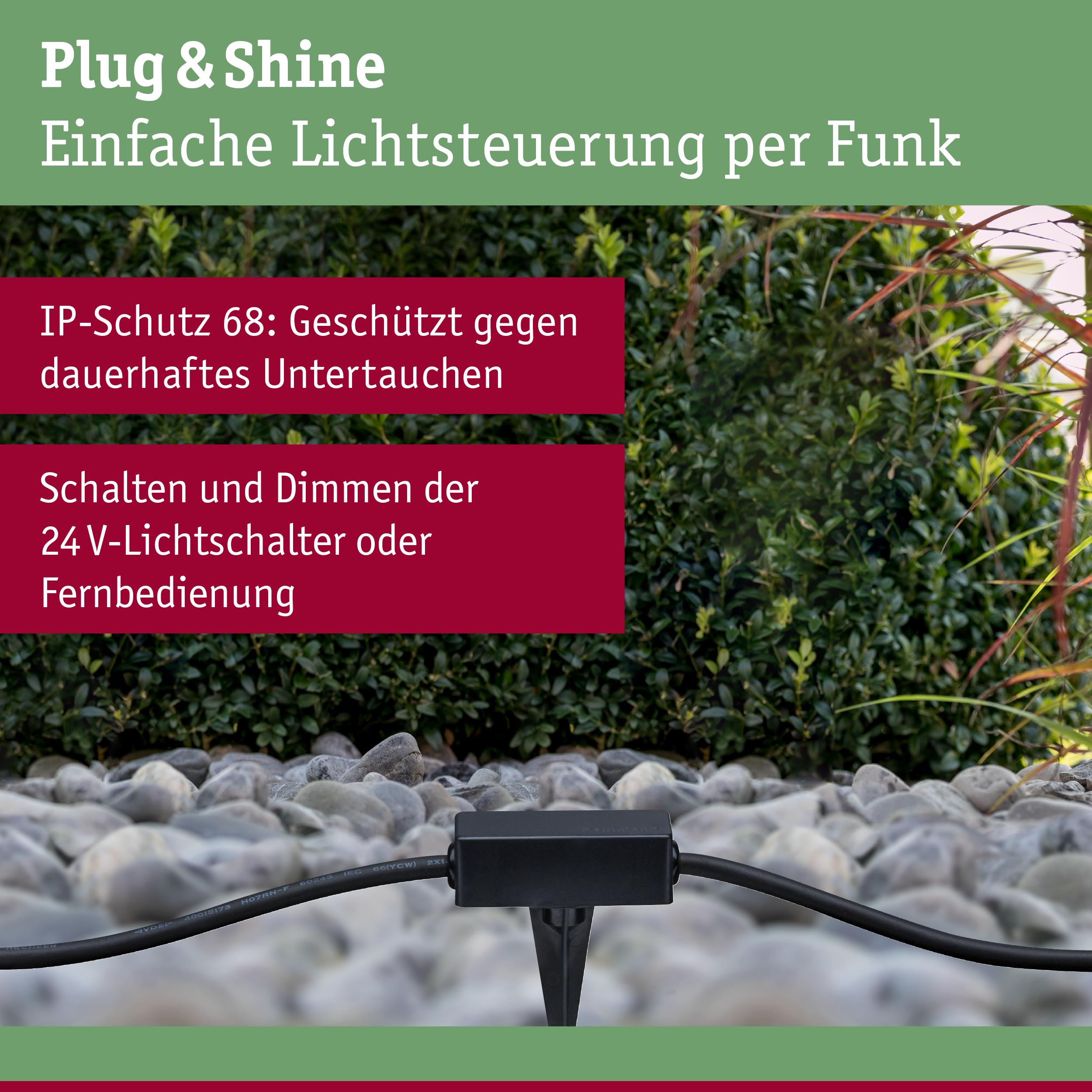 Schwarzes Plug & Shine Funklichtsteuergerät auf Kies vor grünem Busch, IP68 wasserdicht für Außenbeleuchtung