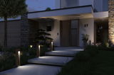 Modern outdoor lighting with warm white LED wooden bollard lights along concrete steps at entrance.