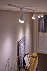 Modern white LED track light with four adjustable spotlights in living space with decor.