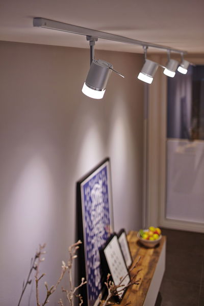 Moderne witte LED-railsverlichting met vier verstelbare spots in woonruimte met decoratie.