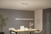 Moderne LED-Pendelleuchte aus Aluminium in Silber über hellem Holztisch mit Laptop und Deko.