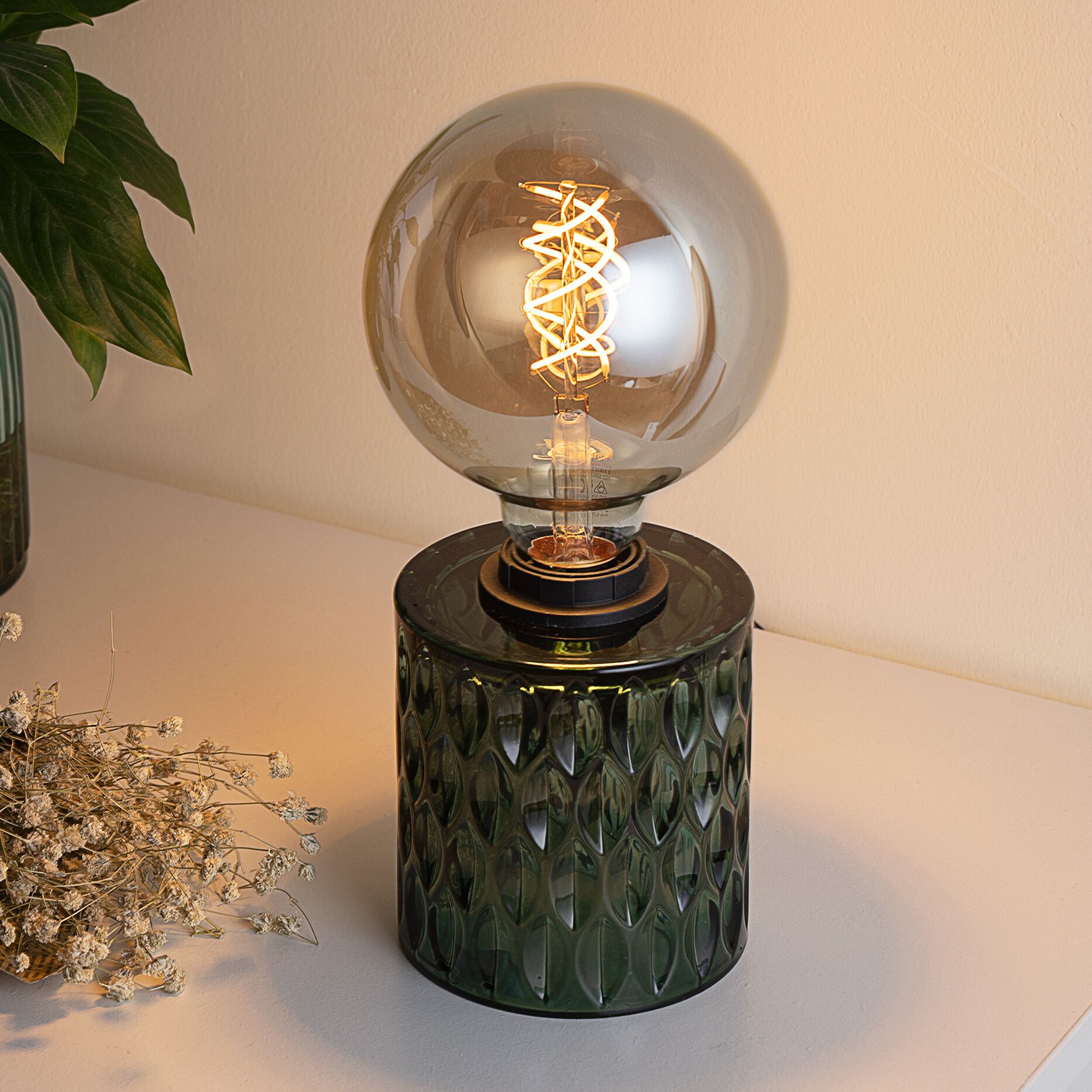 Bordlampe med grøn glasfod og stor rund pære med dekorativ LED-glødetråd.