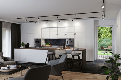 Moderne weiße Küche mit Holzarbeitsplatte und schwarzen Pendelleuchten, stilvolle LED-Beleuchtung.