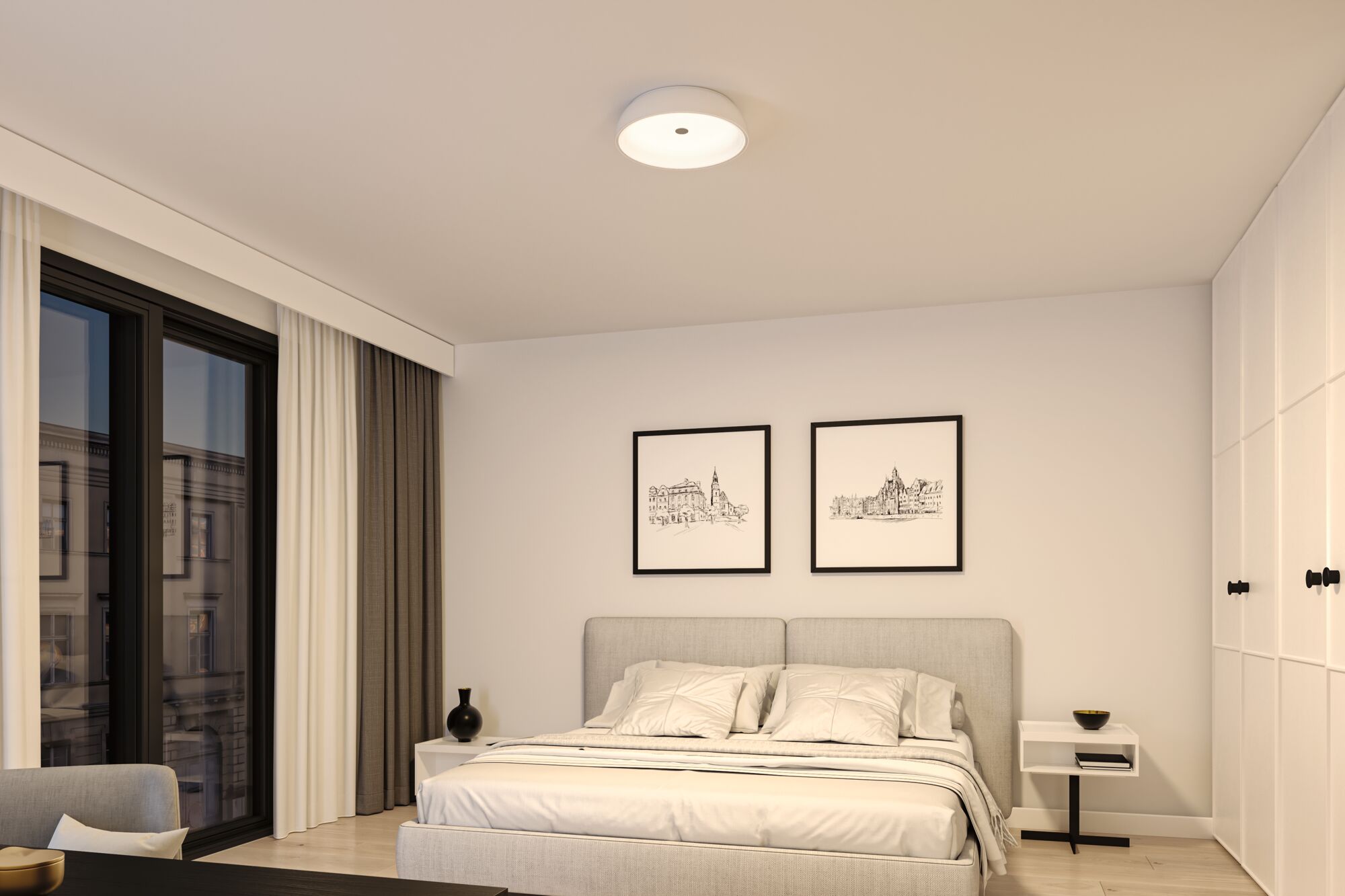 Rundes weißes Deckenlicht aus Kunststoff in modernem Schlafzimmer mit grauem Bett und weißen Wänden.