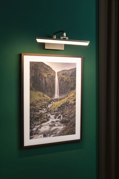 Modern LED picture light in brushed metal on green wall background for illuminating wall art.