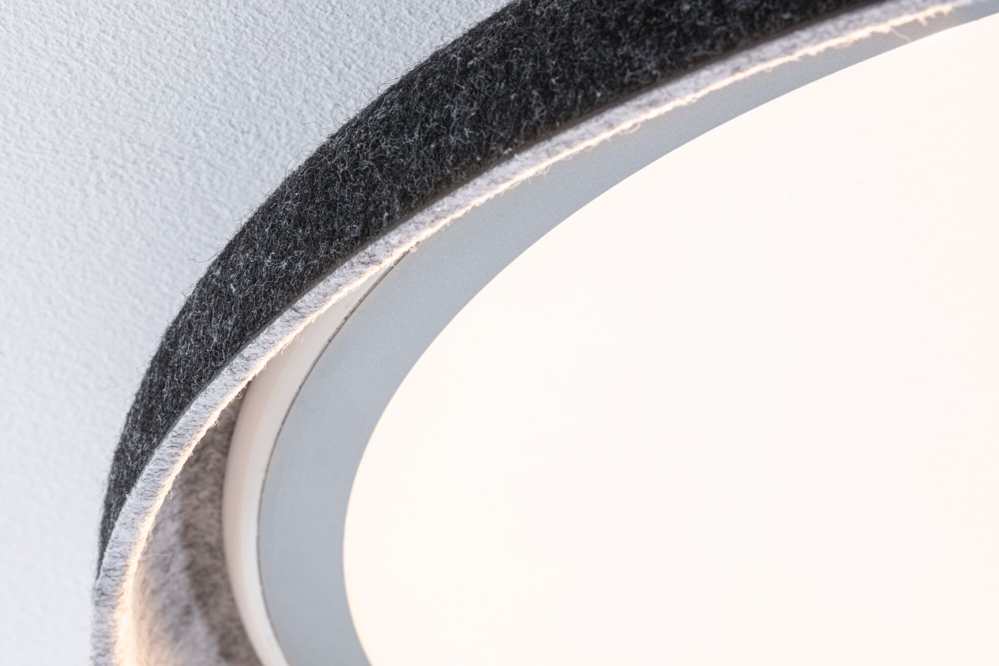 Close-up of round ceiling light with grey felt edge and white diffuser, suitable for modern interiors.