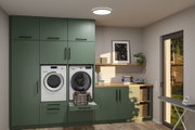 Buanderie moderne intégrée verte avec machine à laver, sèche-linge, plan de travail en bois et panier à linge.