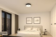 Modernes Schlafzimmer mit grauem Polsterbett, weißen Wänden und schwarzer Deckenleuchte für Wohnraumbeleuchtung
