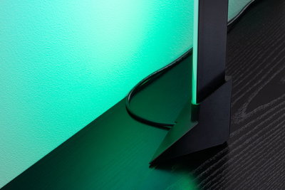 Schwarze LED-Standleuchte mit grünem Licht auf dunklem Holztisch für moderne Raumbeleuchtung