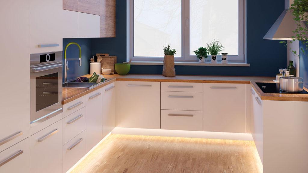 Cuisine moderne blanche avec plan de travail en bois et éclairage LED indirect au sol pour une ambiance chaleureuse.