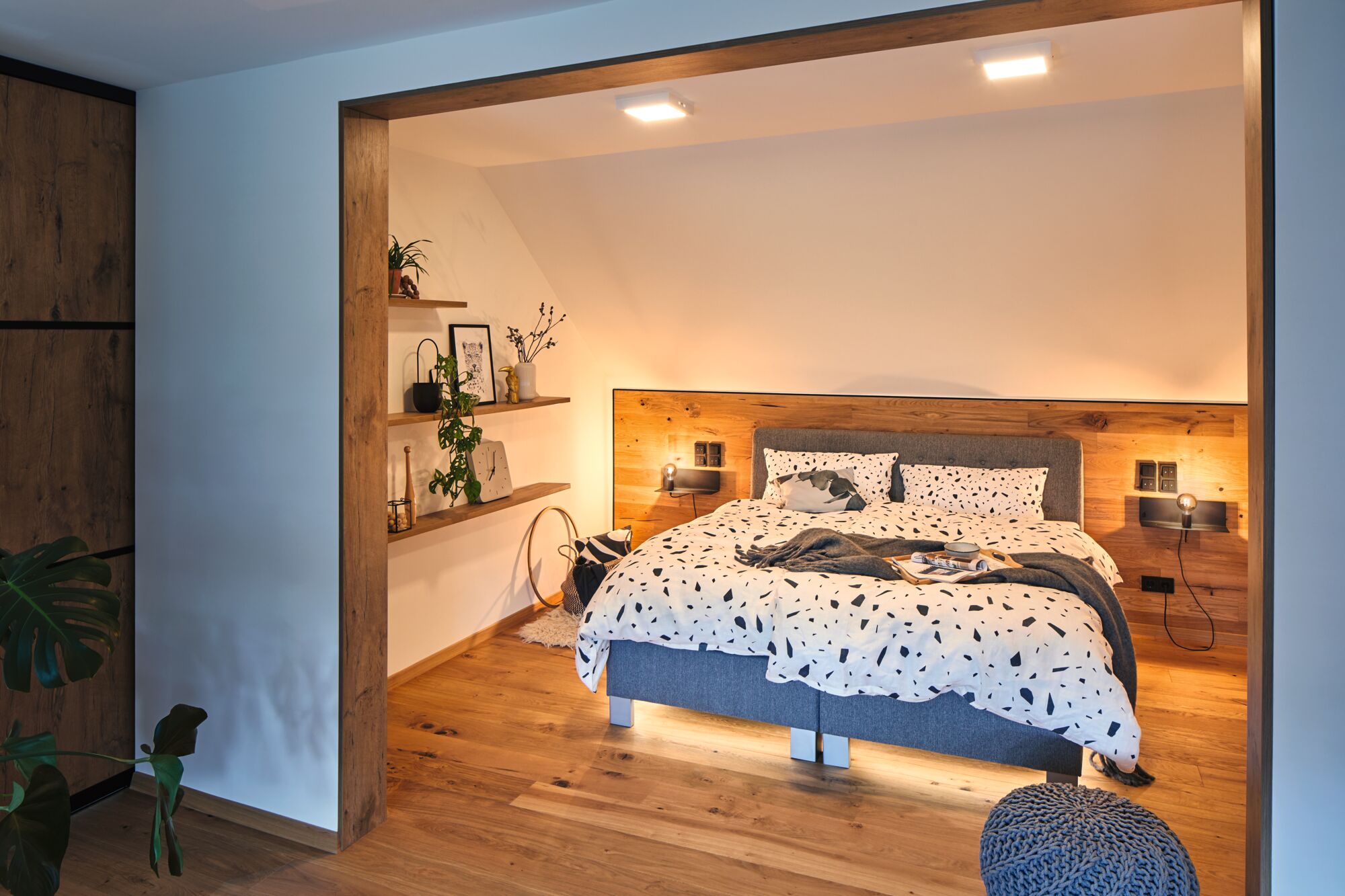 Chambre moderne avec sol en bois, lit gris et éclairage LED blanc chaud au plafond pour une ambiance cosy