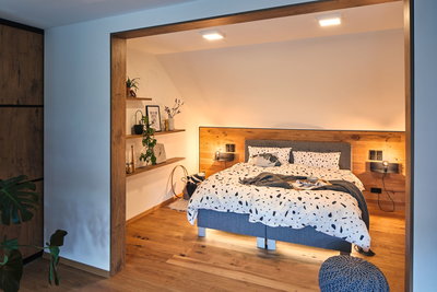 Modern bedroom with wooden floor, grey bed and warm white LED ceiling lights creating a cozy atmosphere