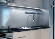 Moderne Küchenzeile mit Edelstahl-Spültisch, schwarzer Arbeitsplatte und LED-Unterbauleuchte