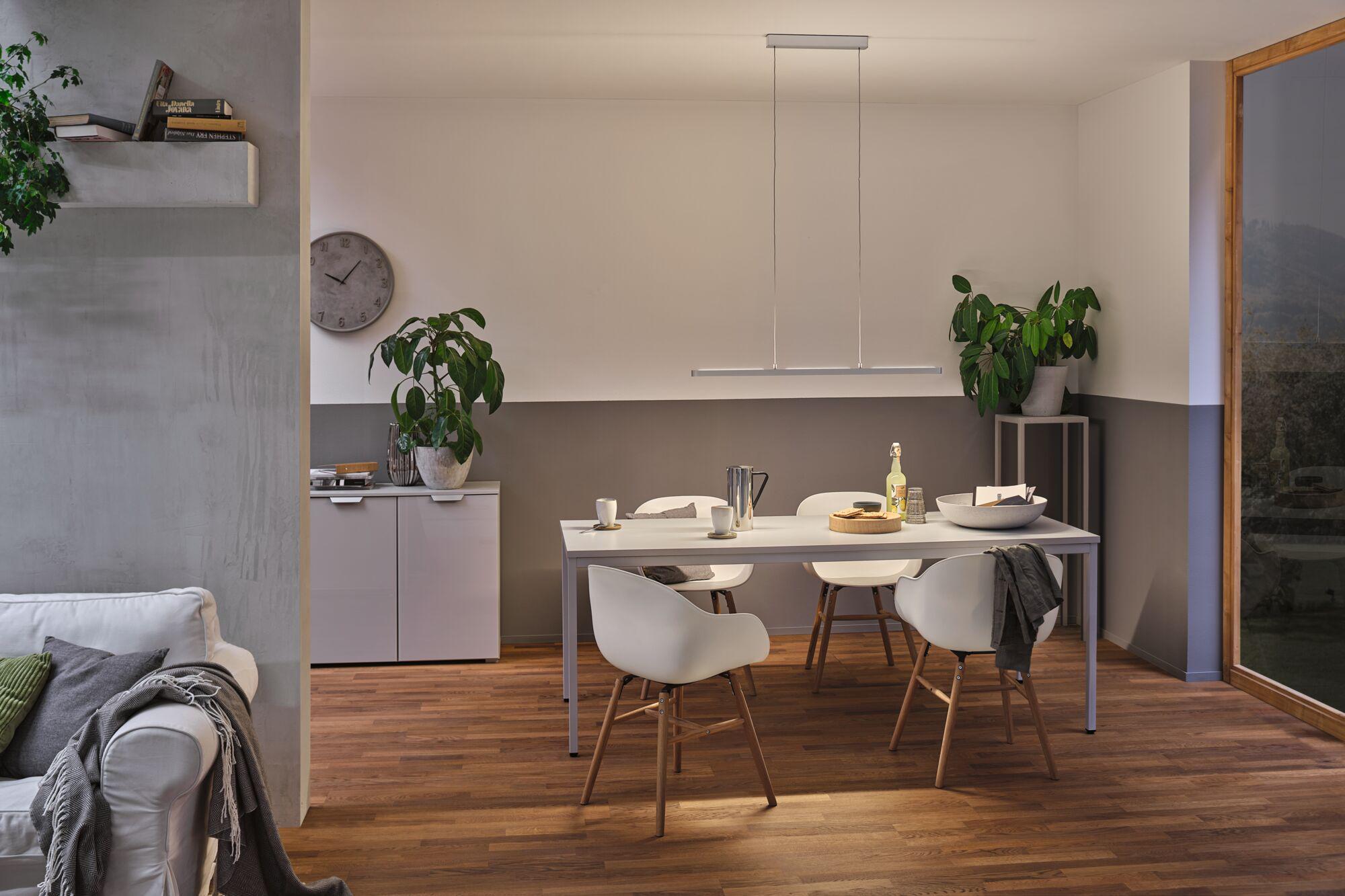 Moderner Essbereich mit weißem Tisch, Holzstühlen und minimalistischer Pendelleuchte in warmem Licht