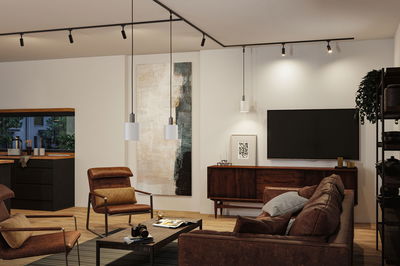 Modern living room with brown leather furniture and white pendant lights on black track lighting.