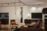 Modern living room with brown leather furniture and white pendant lights on black track lighting.