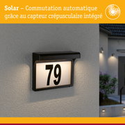 Plaque de numéro de maison solaire noire avec capteur crépusculaire automatique sur mur gris