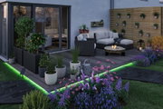 Modern garden with grey polyrattan sofa, wooden deck and green LED floor lighting for outdoor ambiance