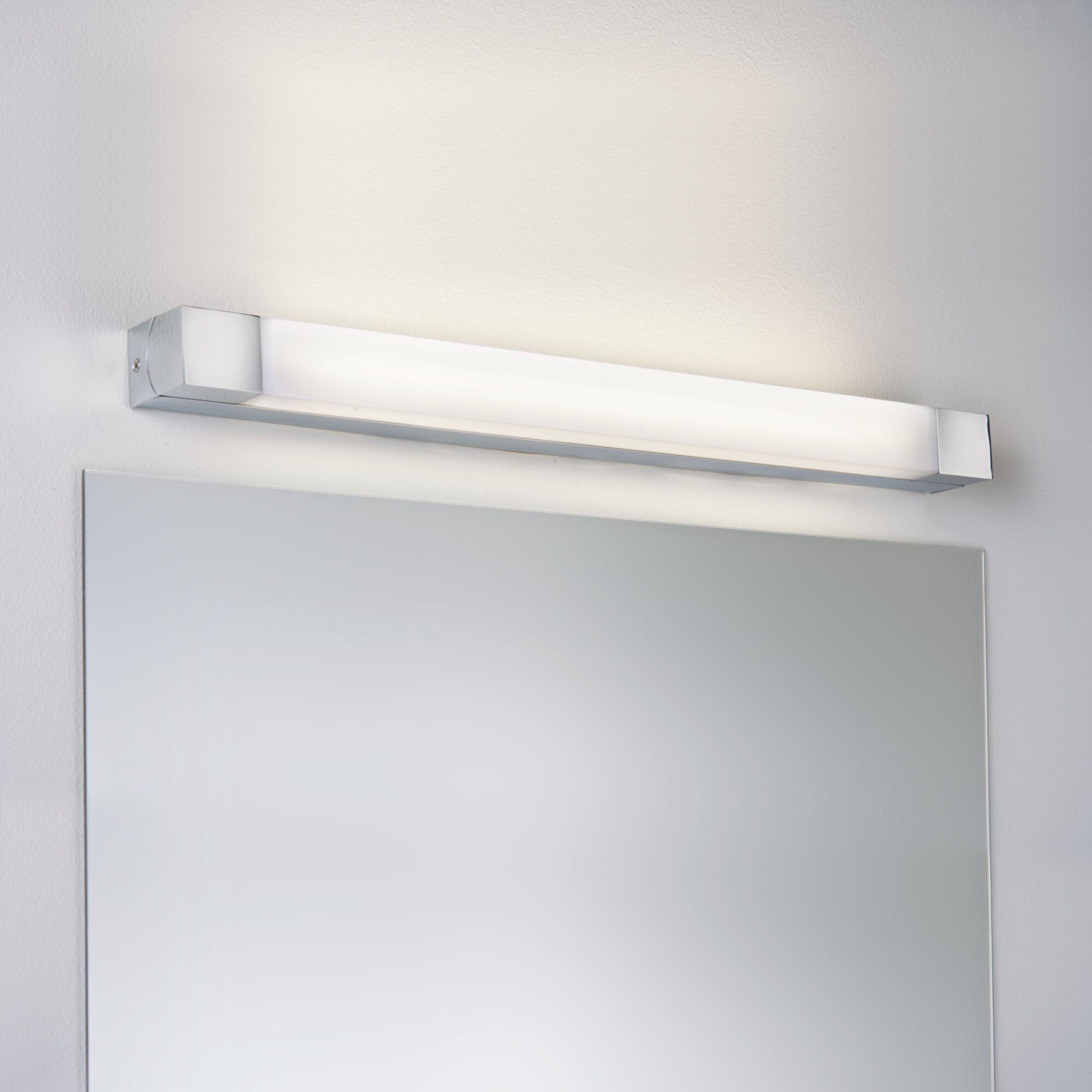 Moderne LED-Wandleuchte in Chrom mit opalem Diffusor über einem Badspiegel für helle Raumbeleuchtung