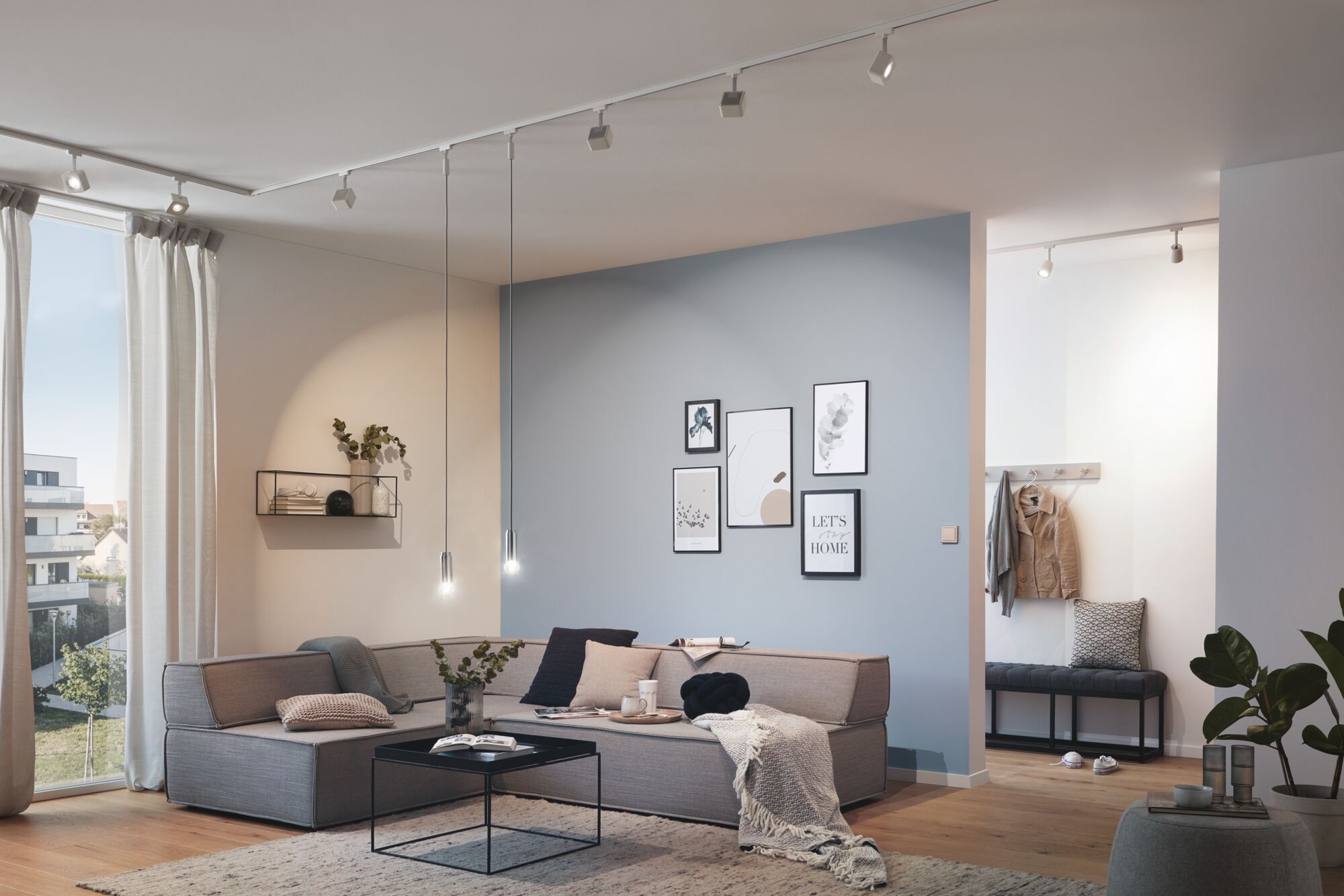 Modern living room with grey corner sofa, black pendant lights, and minimalist blue and white wall decor