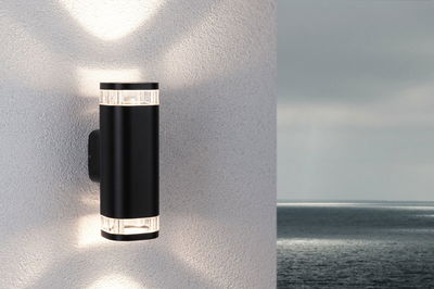 Black aluminum wall light with clear acrylic sections emitting warm white light up and down.