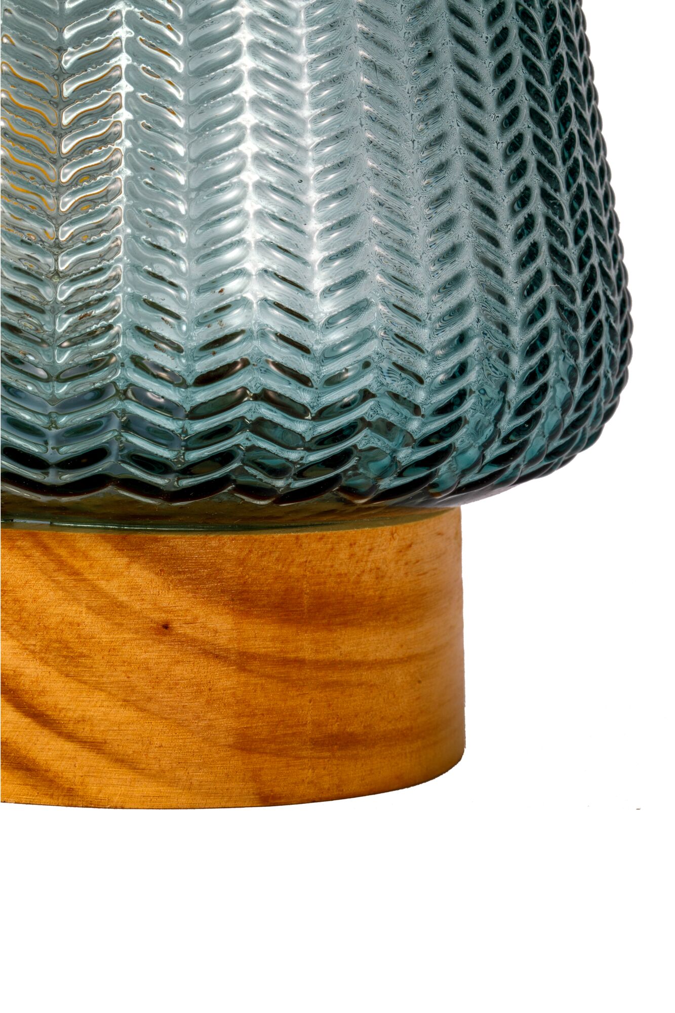 Gros plan sur un abat-jour en verre bleu à motif chevrons sur socle en bois, détail d'éclairage décoratif
